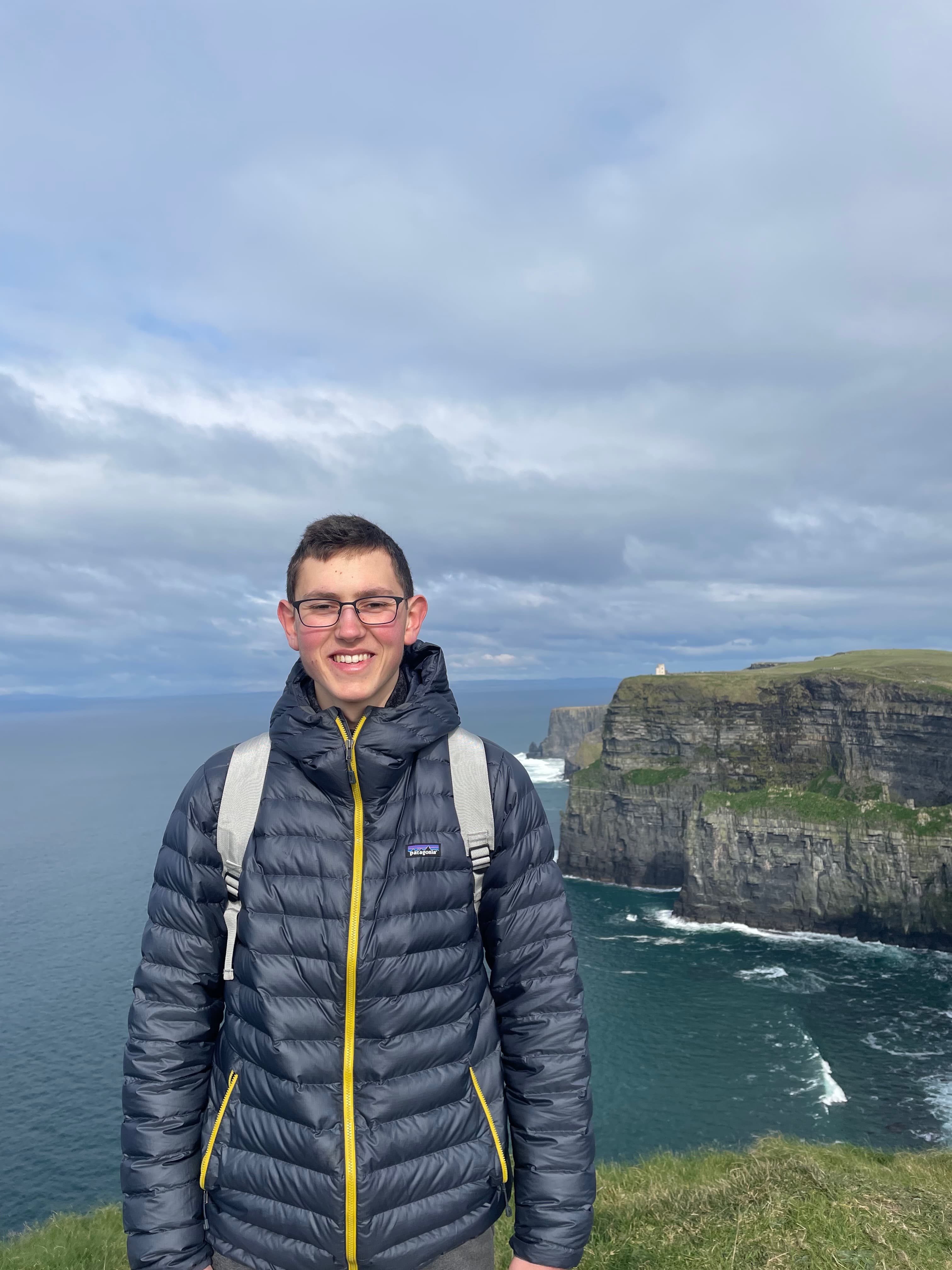 Justin standing in front of the Cliffs of Moher in Ireland.